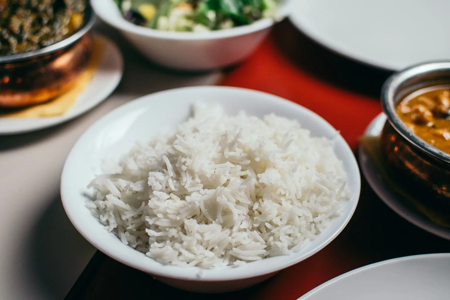 Bol de arroz blanco cocido servido en una mesa junto a otros platos