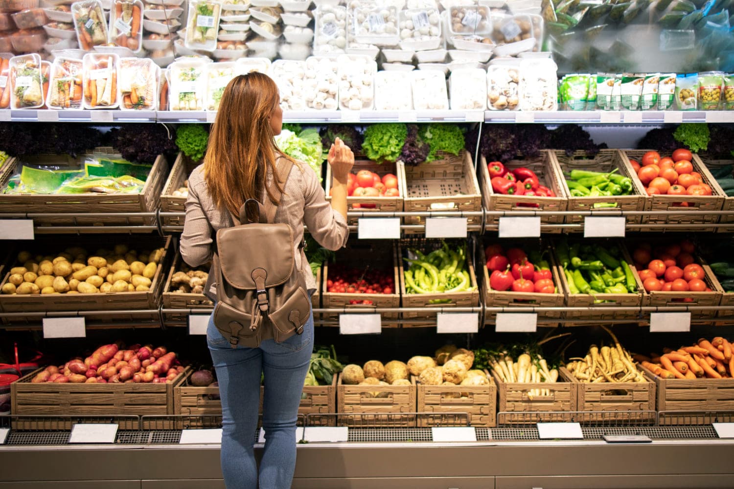 Reponedora en la sección de frutas y verduras a granel de un supermercado